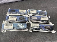 Six sealed packs of blue galaxy-print solar eclipse glasses on grey surface