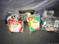 Front view of five of the seven sealed Happy Meal toys showing NHL Ovechkin plush, Hot Wheels car, two Tarzan figures and Space Jam toy