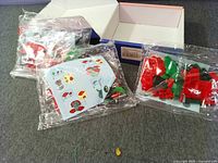 Three sealed bags of red and green bricks, instruction sheet, blue cardboard box