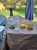 Lot overview showing bird feeder, vase, two amber lanterns on table