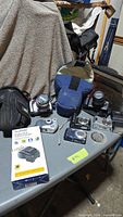 Overall view of table with multiple cameras, cases, boxed charger and film reel