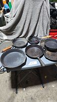 Eight cast iron skillets on table