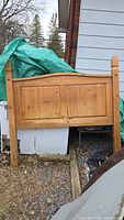 Front view of solid wood queen headboard leaning against structure