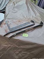 Overview of the three steel tools on tarp: two pry bars, one carpenter’s square