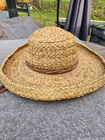 Straw sun hat with chin strap front view on grey surface
