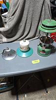 All three items on table: lantern, fuel canister, bell
