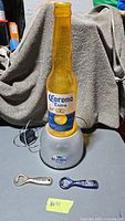 Full view of Corona bottle light on base with two openers in front
