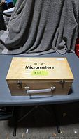 Closed wooden case labeled Micrometers with handle and latches