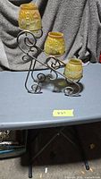 Overall view of metal candle holder with four amber glass votive cups