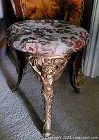 Left front view of ornate gold-painted cast iron stool with floral upholstered seat