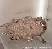 front angled view of shell-shaped silver-plated bowl on marble surface