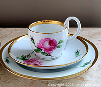 Cup on saucer and dessert plate showing rose decoration and gilt rims