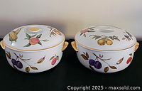 Both casserole dishes with lids showing fruit pattern and gold handles