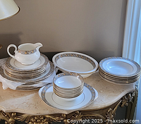 Stacks of plates with gravy boat on stand, soup bowls and platter visible