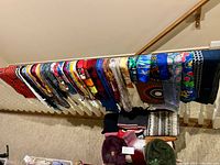 Wide view of scarves hanging on railing with hats below