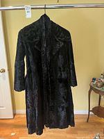Front view of black fur coat hanging, full length visible