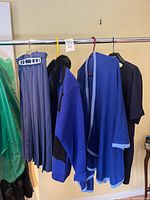 Rack view showing all four garments: pleated skirt, patterned sweater, shawl, plain sweater