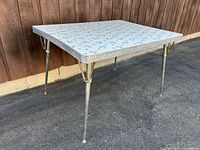 Full view of dining table showing laminate top pattern, chrome legs, brass-tone supports