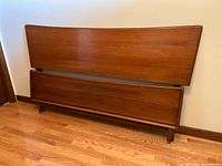Front view of headboard and footboard together showing teak finish and curved design