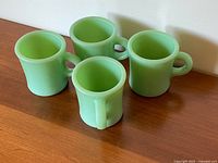 Four jadeite green Fire-King mugs side view