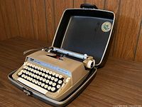 Typewriter in open carry case showing keyboard and platen