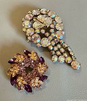 Two rhinestone brooches on neutral background