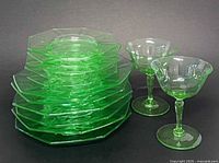 Stack of eleven green octagon plates beside two goblets