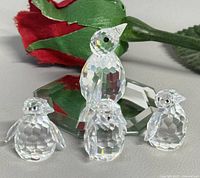 Group shot of all four crystal penguin figurines with reflection mirror and rose for scale