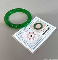 Jade bangle beside authenticity certificate front view