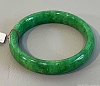 Green jade bangle lying flat showing full circular form