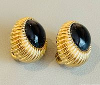 front view showing ribbed gold-tone bezel and black cabochon
