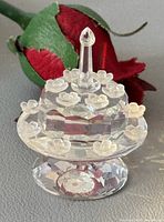Front view of crystal birthday cake on pedestal stand with candle and frosted flowers