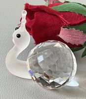profile view of Swarovski crystal snail next to fabric rose