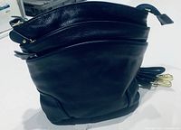 Front view showing three zippered compartments and gold-tone hardware