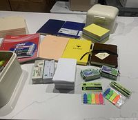 Lot overview showing notebooks, sticky notes, storage boxes, and writing instruments
