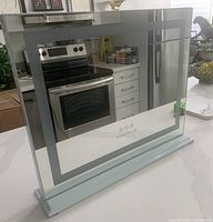 Front view showing mirror surface, LED border, logo, base