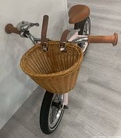 Front view of pink balance bike showing wicker basket, bell and handlebar grips