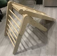 Side view of assembled Pikler triangle with ramp attached at top showing ladder rungs and plywood panels