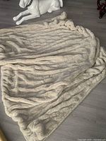 Full view of cream faux fur ruched throw spread on floor