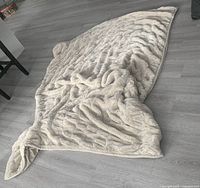 Full view of cream faux-fur ruched throw laid on floor