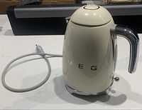Front view of cream Smeg electric kettle with cord visible