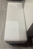 Top view of white faux leather storage ottoman closed