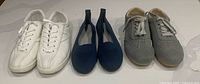 All three pairs aligned: white sneakers, navy flats, grey sneakers