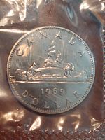 Obverse side of 1969 Voyageur dollar through mint cellophane