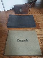 Camera case, black album, tan album on floor