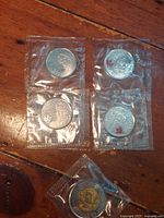 Five sealed coins showing four 25-cent pieces and one $2 piece