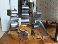 Full view of ship-form clock showing wood hull, metal sails, and clock face