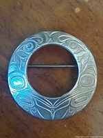 front view of circular engraved silver brooch