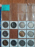 Album page showing nine of the nineteen commemorative dollars in flips
