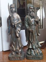 Full view of both bronze-tone resin figurines side by side